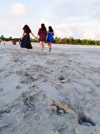 Rear view of women on beach against sky