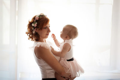 Gentle mother and daughter on the bed in a real room, the concept of motherhood and affection