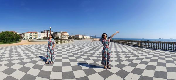 People walking on tiled floor against blue sky