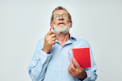Portrait of senior man holding key against white background