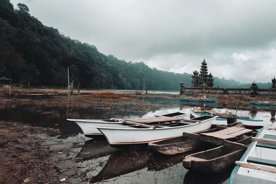 Boats moored on shore against sky