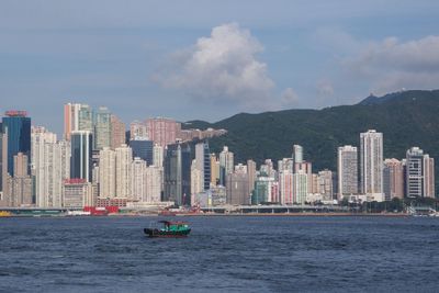 Boat in river against tall buildings