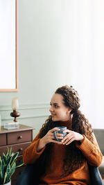 Portrait of young woman sitting on sofa at home