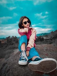 Full length of woman sitting on land against sky