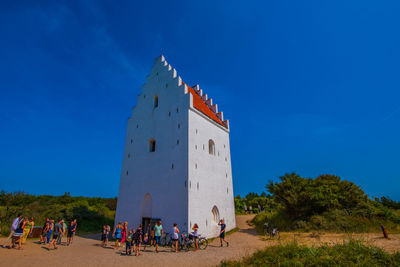 Group of people by building against blue sky