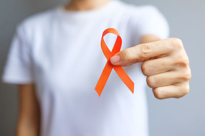 Close-up of man holding red standing against wall