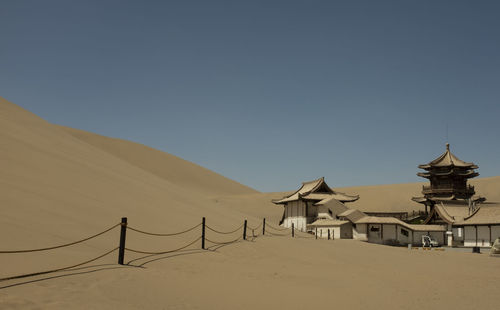 View of desert against clear blue sky with historical chinese building 