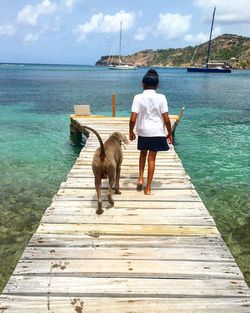 Rear view of woman standing on jetty in lake