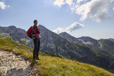 Portrait of hiker standing on mountain against sky