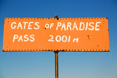 Low angle view of road sign against clear blue sky