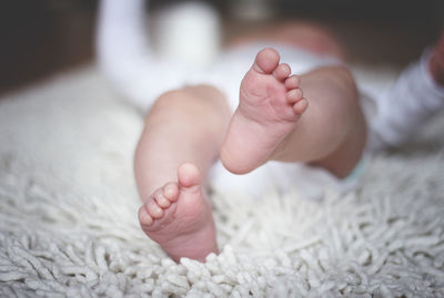 Low section of baby lying on bed