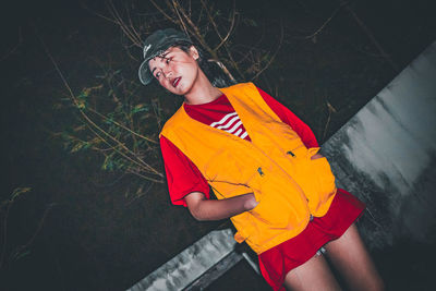 High angle view of young woman standing against yellow wall