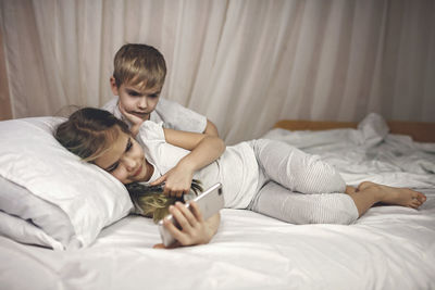 Siblings watching video in mobile devices in bed, gadget dependence and addiction, online lifestyle