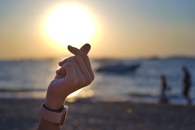 Human hand on beach during sunset