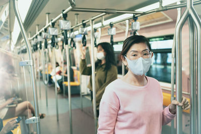 Portrait of woman wearing mask while standing in train