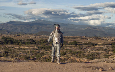 Portrait of man standing on landscape against mountains