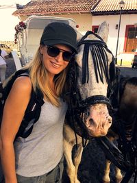 Portrait of woman in sunglasses standing with horse