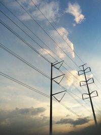 Low angle view of electricity pylon against cloudy sky