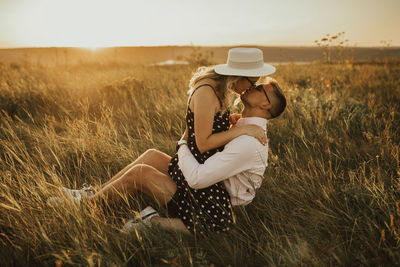 Side view of couple kissing whiles sitting on grass