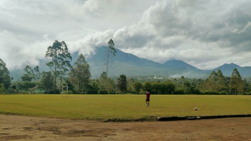 Man playing soccer on field against mountains