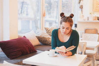 Young woman using mobile phone while sitting on table