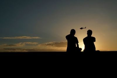 Silhouette people looking at sunset