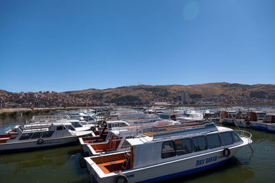 Sailboats moored at harbor against clear blue sky