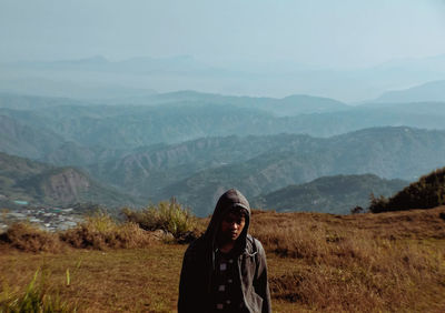 Young woman standing on mountain against sky