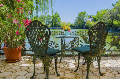 Empty chairs and table in park against sky
