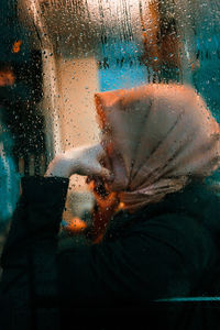 Rear view of woman looking through window