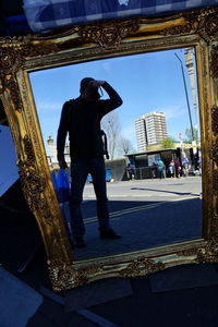 Rear view of man photographing against sky in city