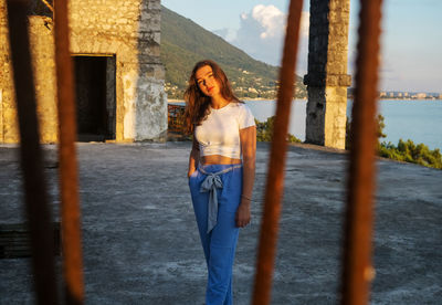 Portrait of young woman standing against built structure