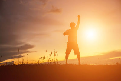 Silhouette man standing on field against sky during sunset