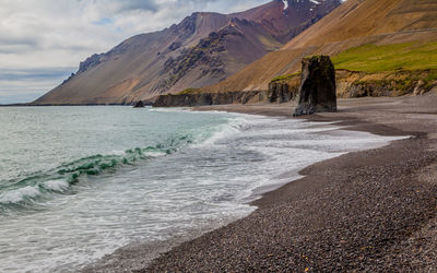 Waves lap the gravel rock beach in a desolate stretch of the dramatic wild icelandic coast in summer