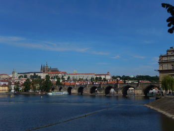 Arch bridge over river in city against blue sky