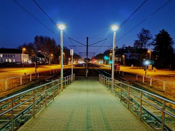 Illuminated railroad tracks against sky at night