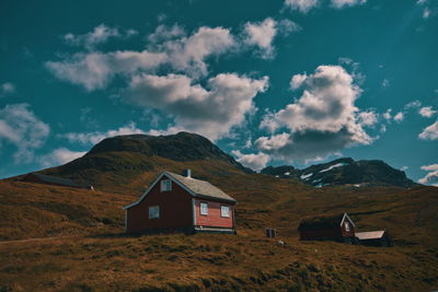 Built structure on field by mountain against sky