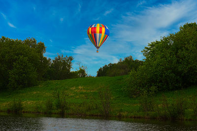 Hot air balloon flying over trees against sky