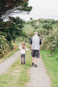 Father and daughter walking down scenic track holding hands