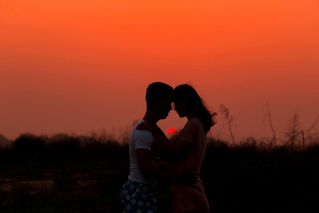 two people, togetherness, sunset, love, couple - relationship, bonding, sky, women, standing, embracing, positive emotion, adult, orange color, heterosexual couple, real people, emotion, three quarter length, silhouette, men, leisure activity, hairstyle