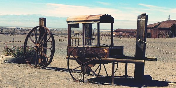 Old rusty sales stand on field against sky