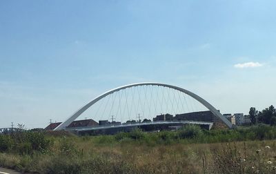 Arch bridge on field against sky