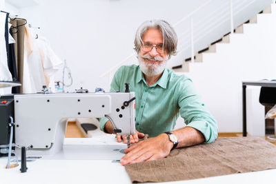 Portrait of smiling fashion designer sewing at studio