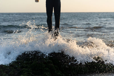 Low section of man walking on beach