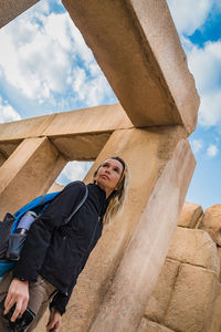 Low angle view of woman standing by column against sky