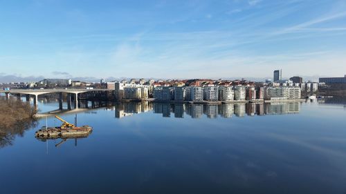 Buildings and bridge by lake against sky