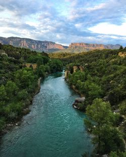 High angle view of river amidst trees against cloudy sky