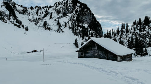 Snow covered landscape and houses against sky