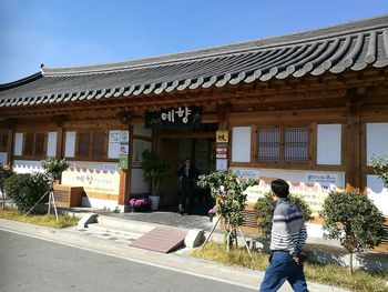 Man standing by building against clear sky