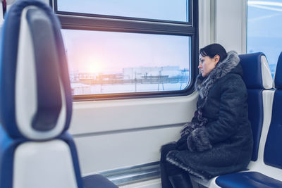 Rear view of man sitting on train window
